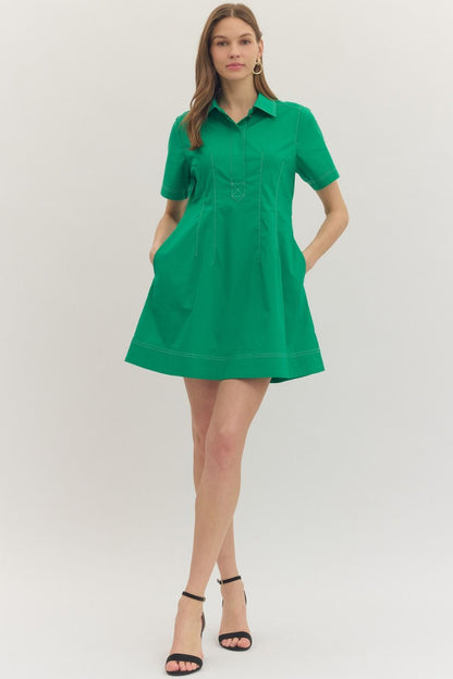 Solid short sleeve mini dress featuring stitch detail at front placket. Hidden button closure at front. Side pockets. Lined. Woven. Non-sheer. Lightweight.